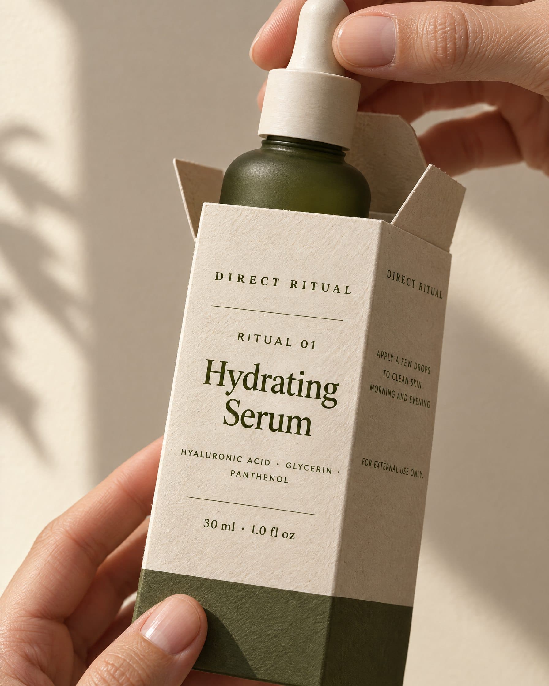 Hands drawing the Hydrating Serum out of its Direct Ritual carton